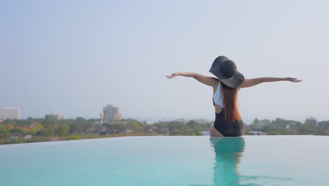 Happy-Woman-near-Swimming-Pool-Spreading-Arms-enjoying-Holiday,-Rear