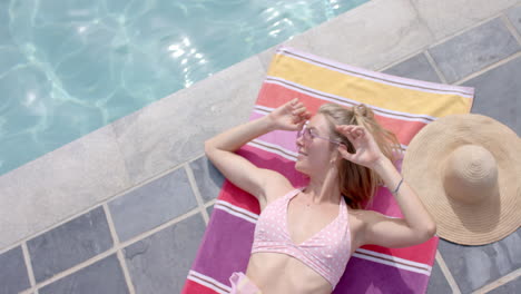 young caucasian woman enjoys the sun by the pool