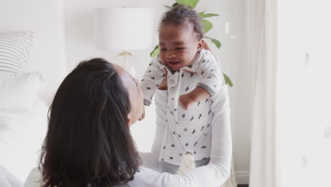 Madre-Milenaria-Afroamericana-Levantando-A-Su-Bebé-Y-Sonriéndole,-Vista-Por-Encima-Del-Hombro