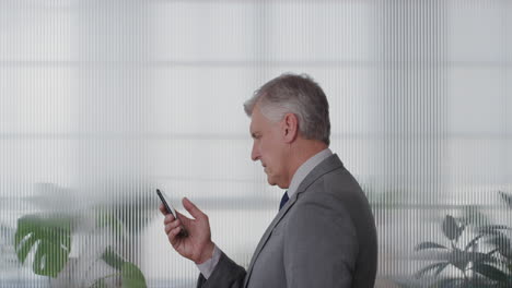 portrait happy mature businessman executive using smartphone in office enjoying texting browsing messages sending email sms on mobile phone slow motion side view