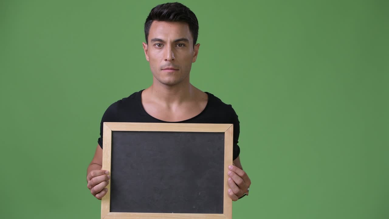 joven y guapo hombre hispano contra un fondo verde