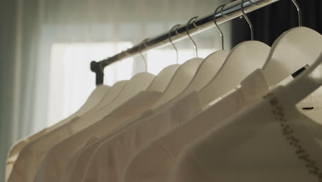 Rack-with-hangers-of-white-clothes-in-the-rays-of-the-sun-from-the-window