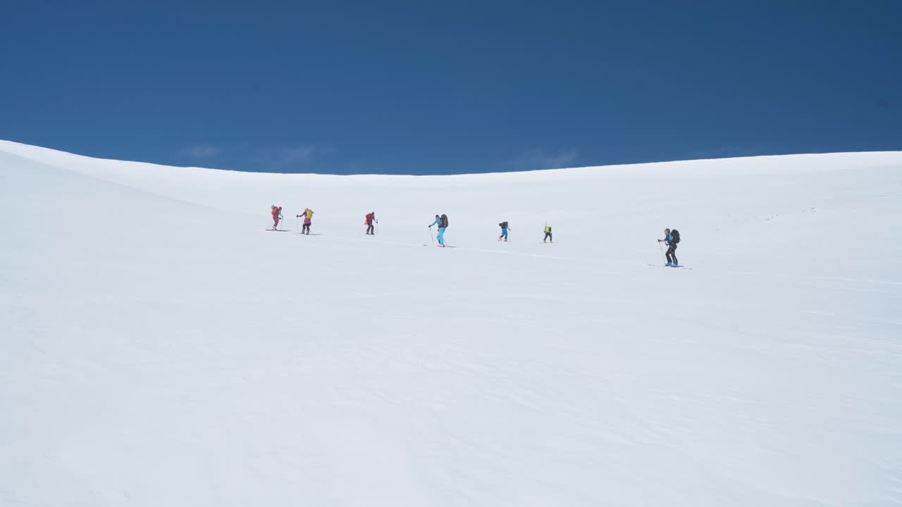 스발바르의 가파른 눈 덮인 슬로프를 등반하는 등산객 팀, 벨로우에서 보기