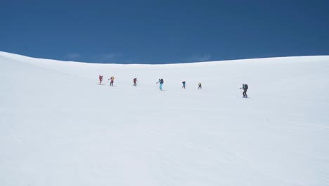 equipo de excursionistas subiendo una empinada pendiente nevada en svalbard, vista desde abajo