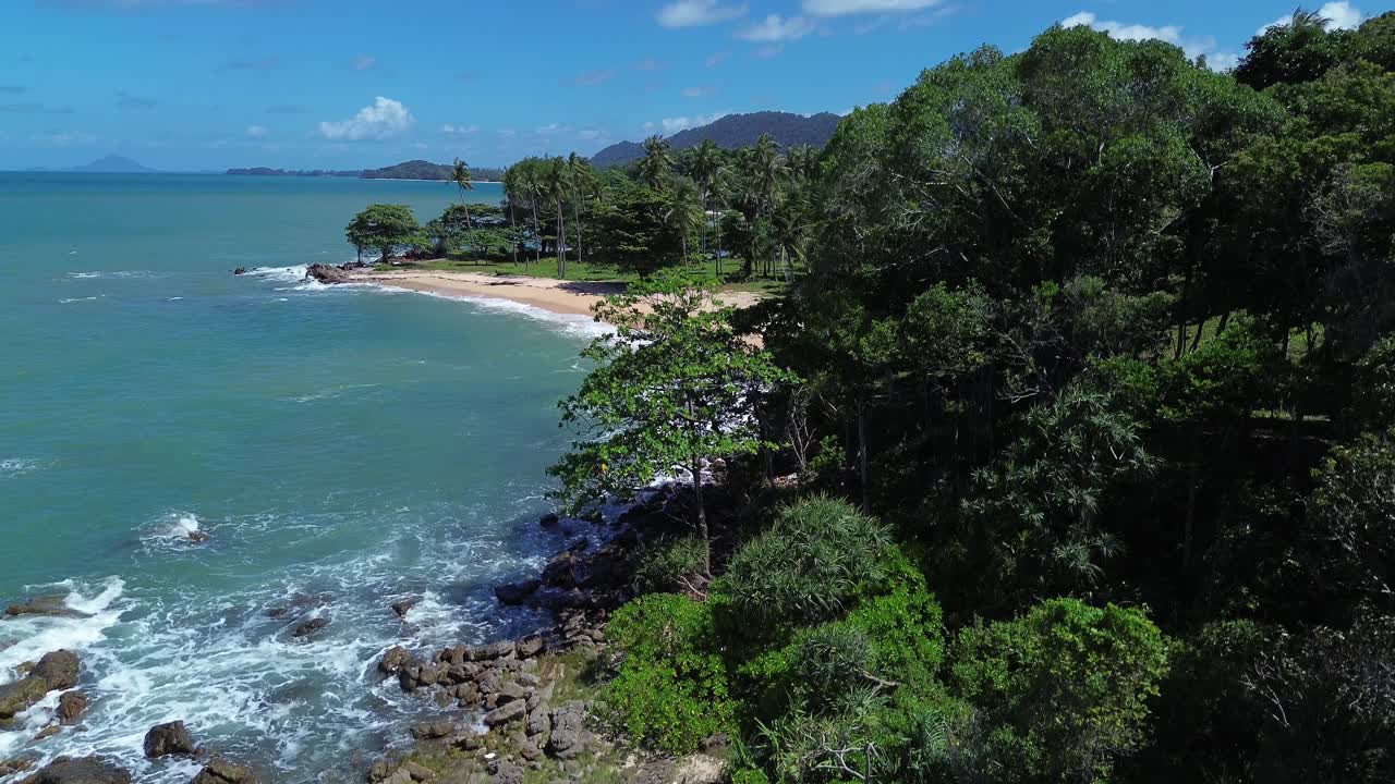 Cinematic drone aerial slowly rise above lush tropical forest on Koh Lanta, Thailand. Revealing a remote paradise beach with turquoise ocean water, white sand, and untouched coast with no people