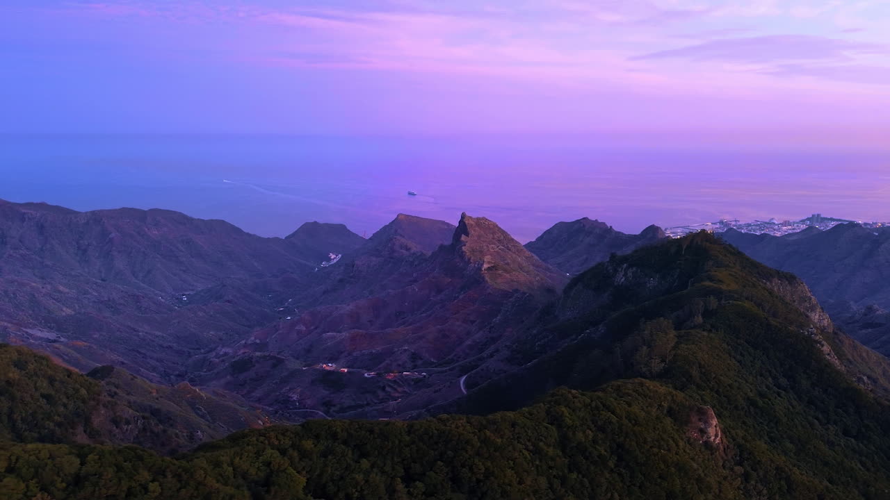Spectacular rocks from drone footage at sunset. Calm waterscape of the Atlantic Ocean merging with the violet sky at backdrop. Tenerife, the Canary Islands, Spain
