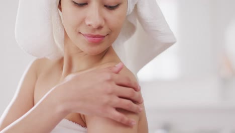 video of portrait of smiling biracial woman with towel on hair in bathroom