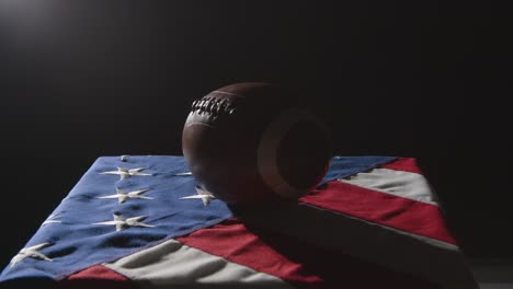 low key lighting studio shot of american football on stars and stripes flag 2