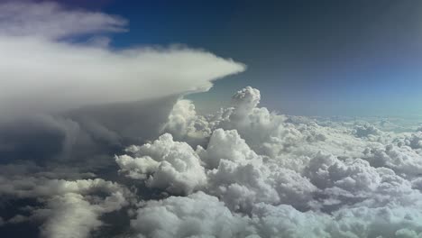 an immersive aerial pilot’s view of massive storm clouds under an intense color blue sky.