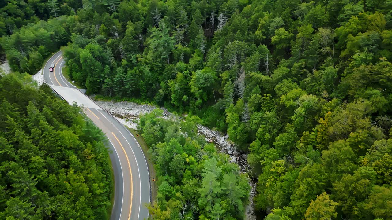 Tilted drone fly along the curved part of Mohawk Trail scenic road cutting through dense forests, Berkshire, Massachusetts, USA
