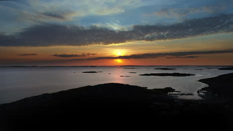 aerial beautiful sunset with vivid and cinematic colours at a rocky coastline with a marina and islands in an archipelago