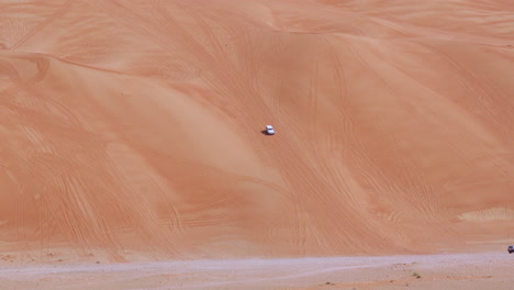 4wd vehicle goes off-road in huge desert sand dunes in sharjah, united arab emirates - wide shot