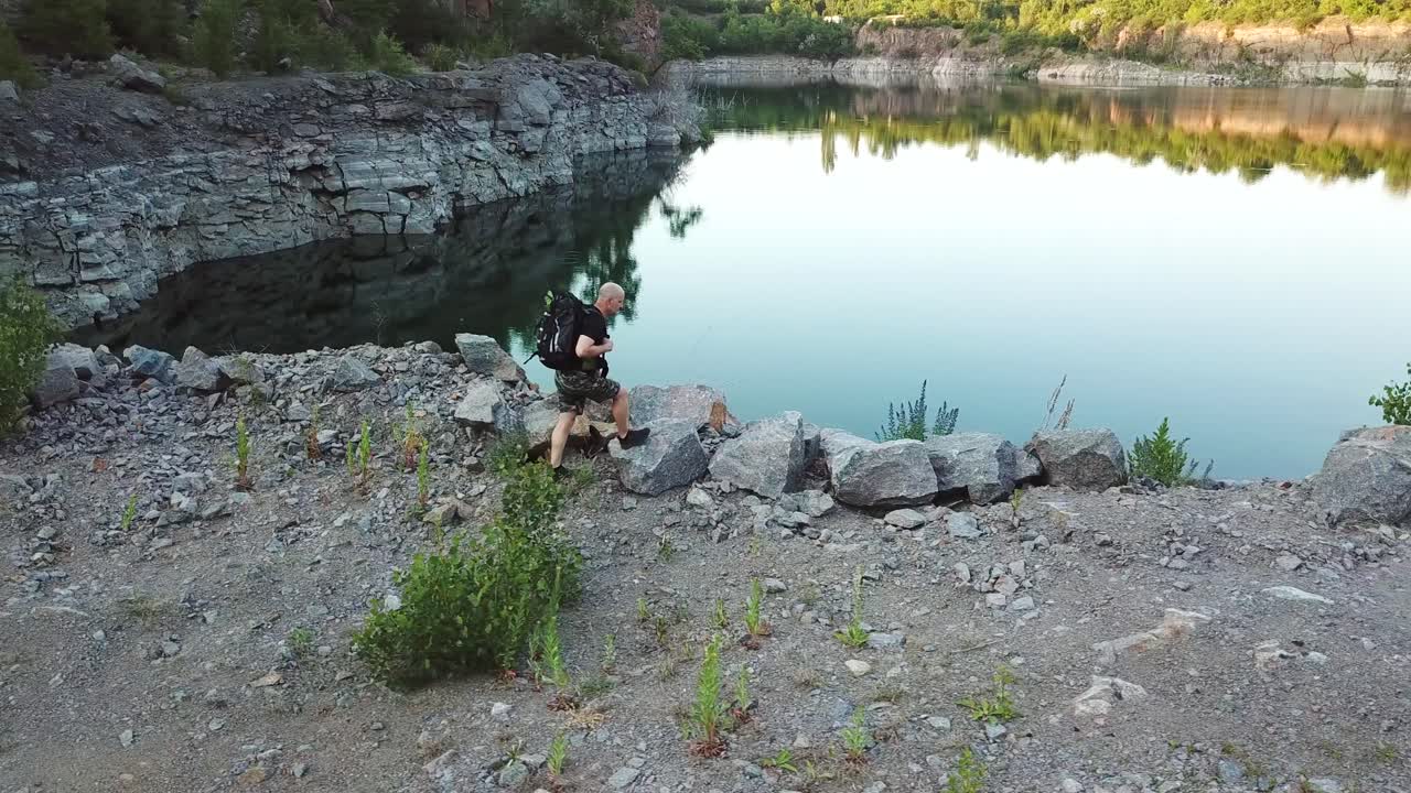 Aerial view of a tourist walks along the rocky shore of a lake. Traveler on the cliff. Camping season