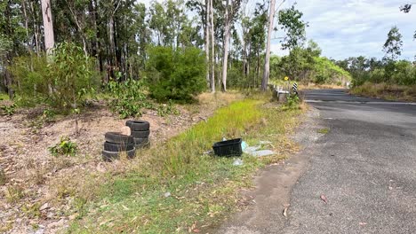 a series of mailboxes and litter along a rural australian road, surrounded by trees and natural vegetation