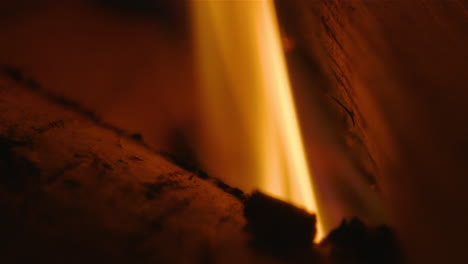 extreme close up of a flame coming up between two logs, 60fps