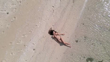 long black hair and a brown bikini create a vision of beach perfection as a sexy girl relaxes by the shore