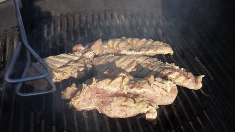 flipping organic chicken breasts on the barbeque grill with tongs - isolated slow motion