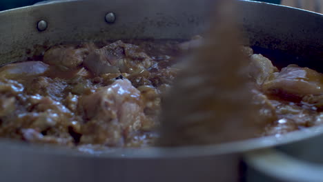 trozos de pollo revueltos en salsa de curry en una olla