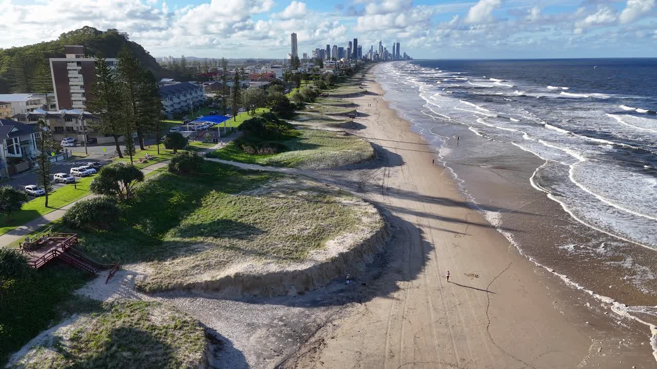 Drone footage captures beach erosion along Gold Coast, Australia, with visible urban skyline and dynamic ocean waves