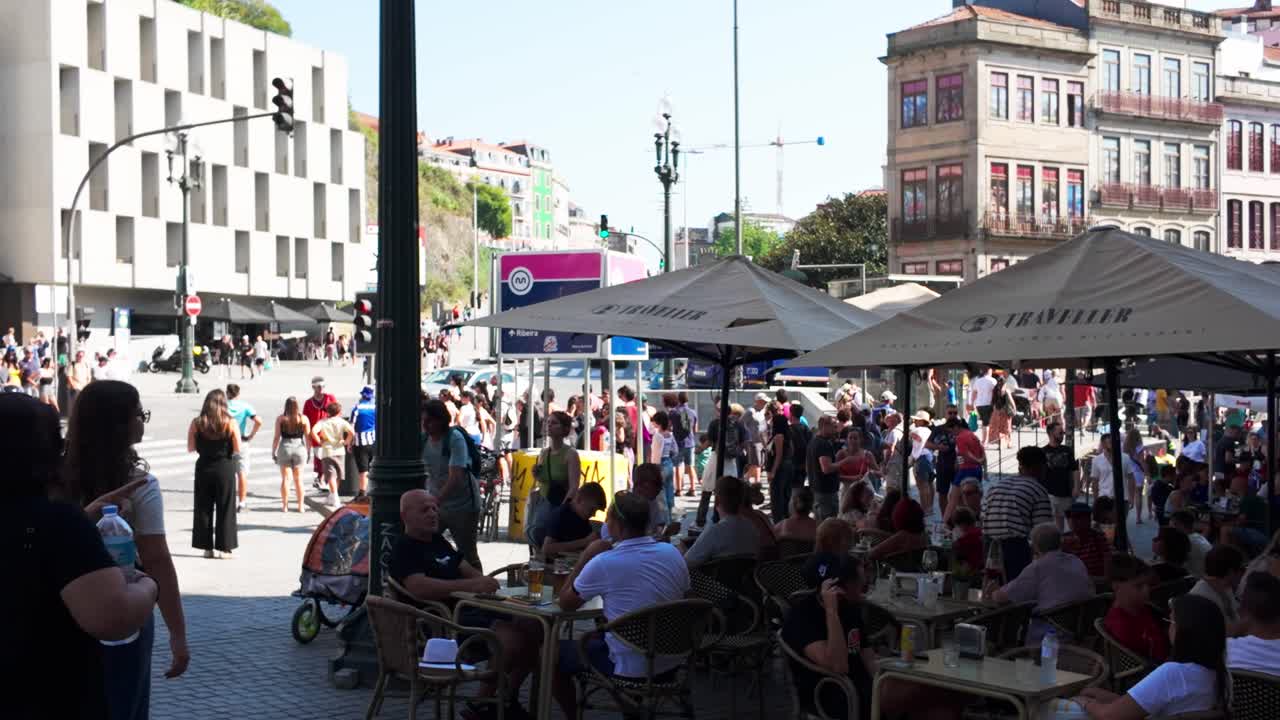 Busy summer day at Praça de Almeida Garrett with outdoor cafes and crowds enjoying the lively scene