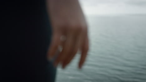 closeup hand girl standing on hilltop sea beach. woman enjoying view calm ocean.