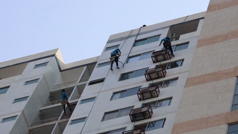 workers cleaning windows on a tall apartment building