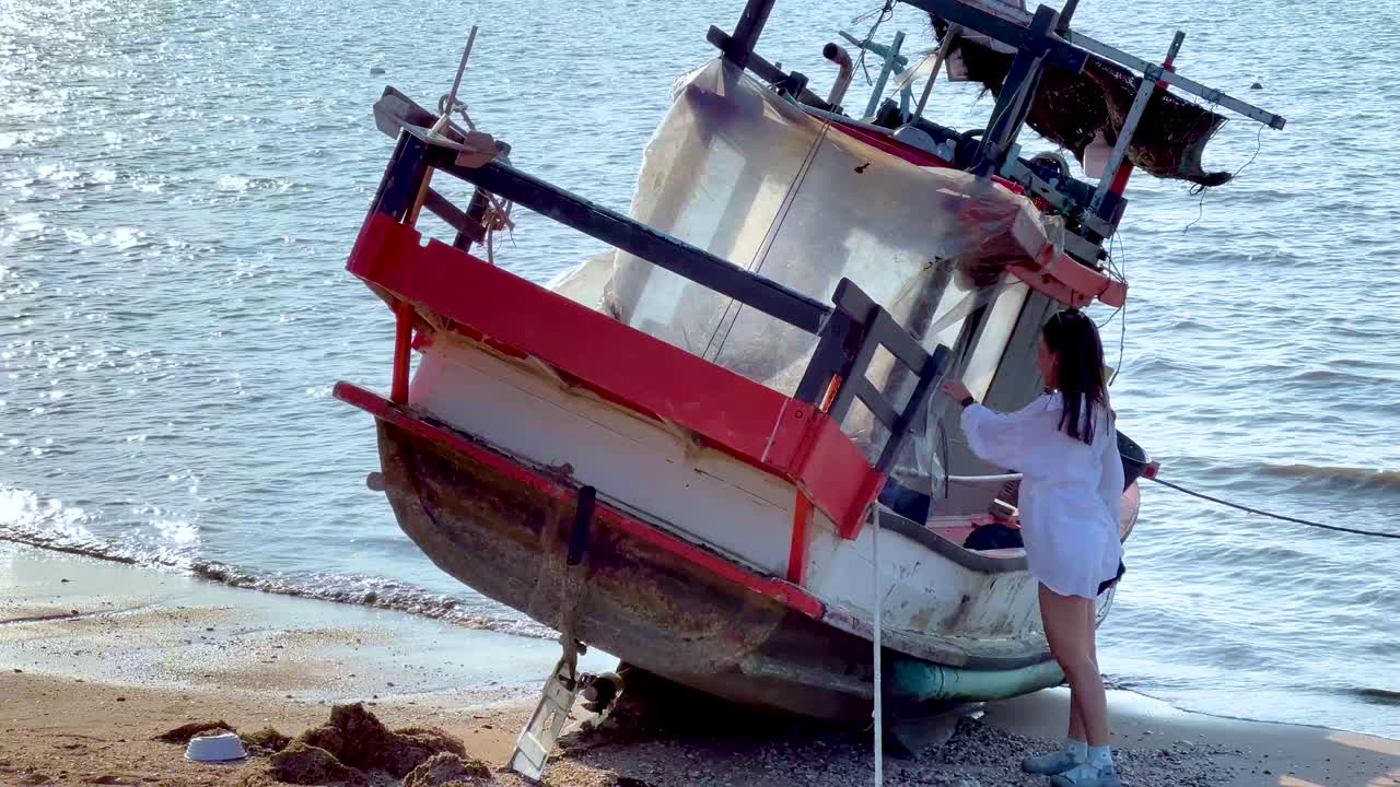 Girl examines boat on Chonburi beach