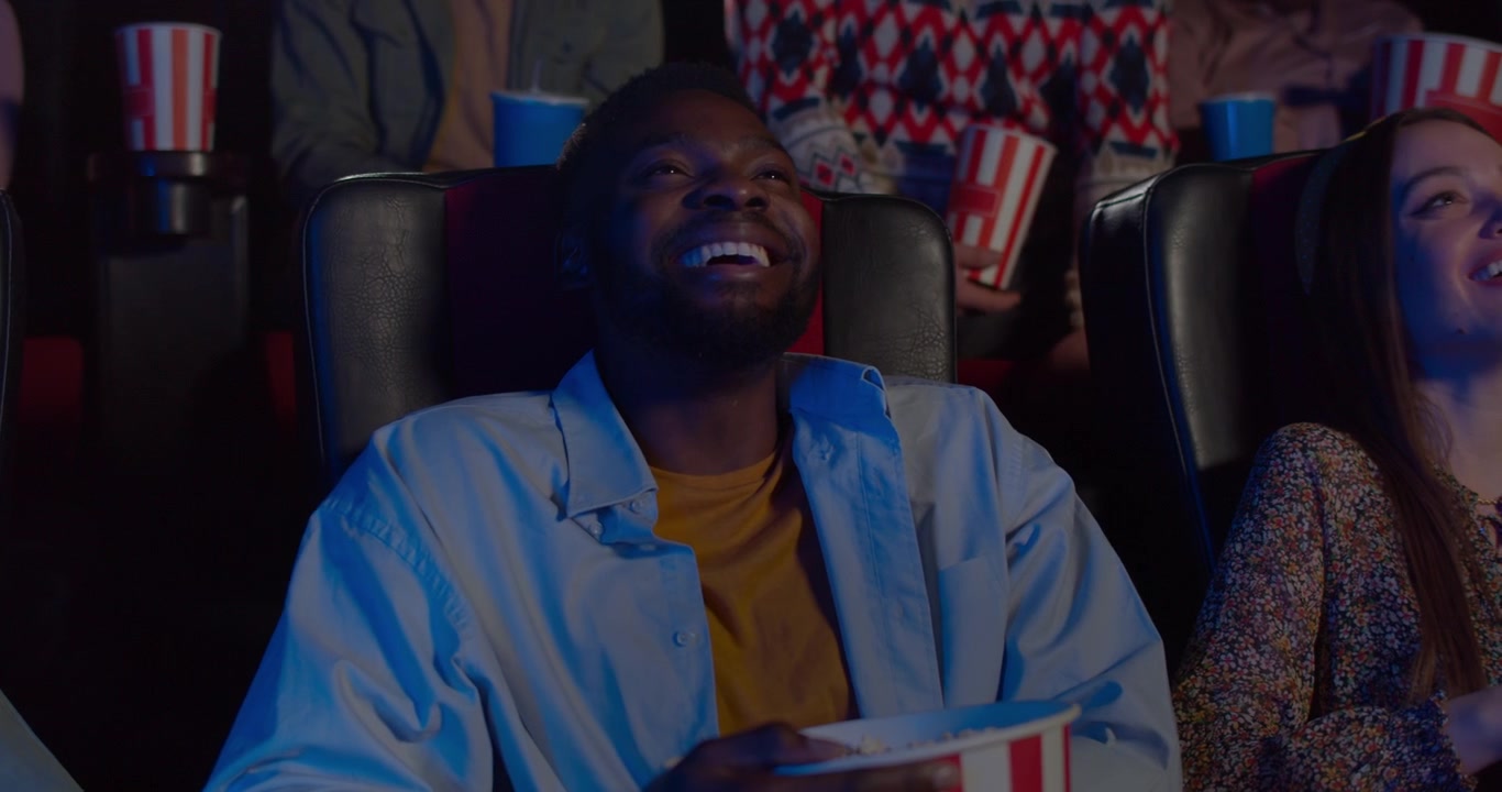 Young Man Laughing While Watching a Movie in a Cinema