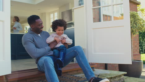 father and son sitting on step at home playing and having fun together