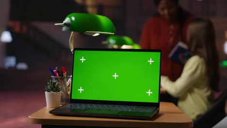 students studying in library with green screen laptop