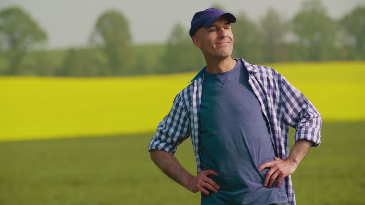 Agricoltore maturo sorridente che esamina il campo agricolo