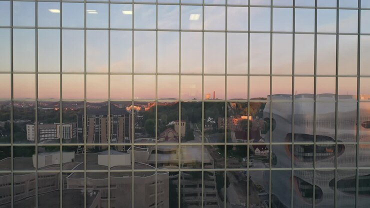Reflejo de paisaje urbano en ventanas de edificios modernos al atardecer