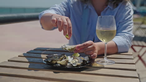 woman eating oysters and drinking wine by the ocean