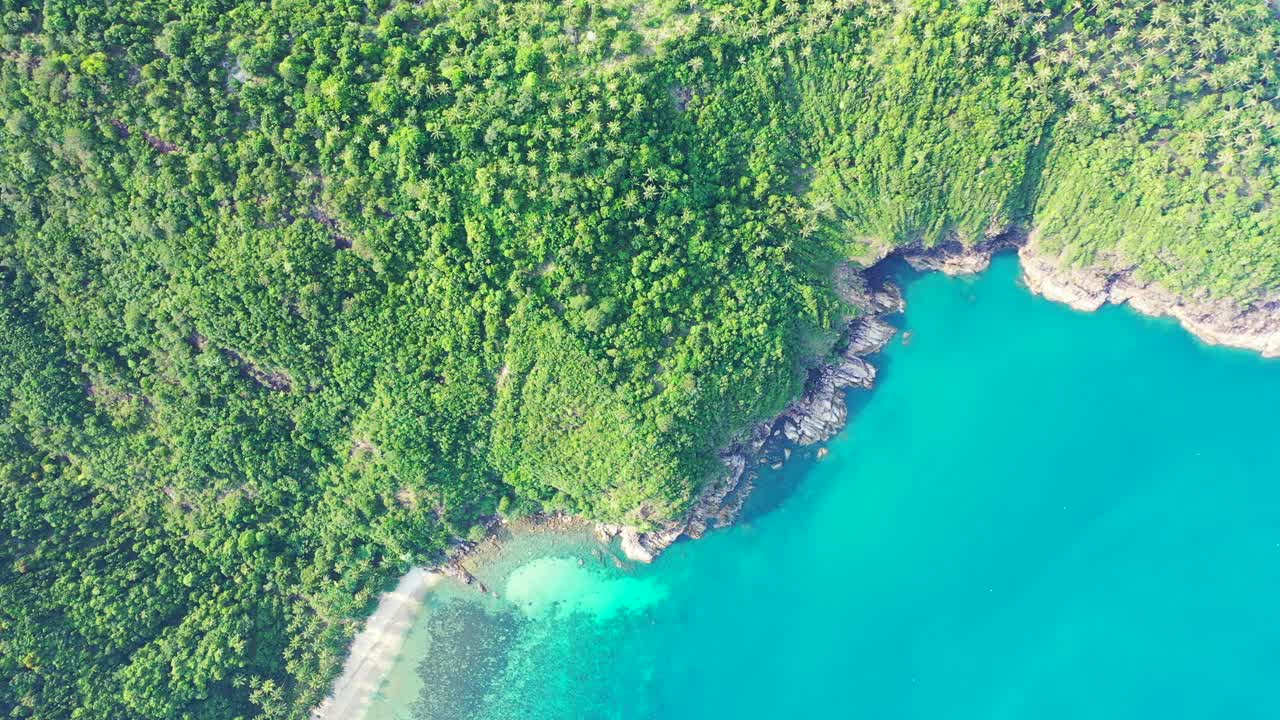 태국 청록색 바다의 잔잔한 맑은 물로 씻은 바위 해안선이 있는 열대 섬 언덕의 푸른 무성한 초목