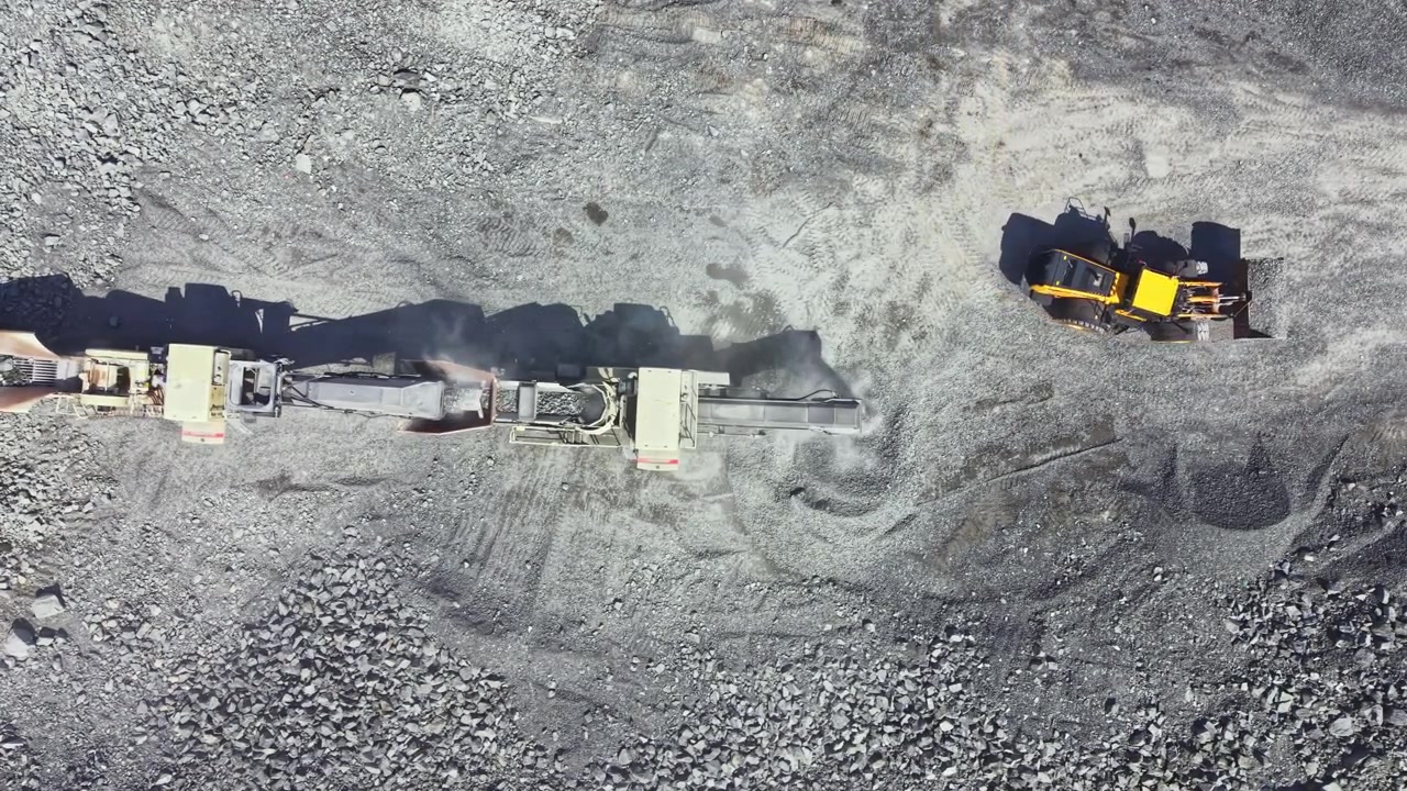 Granite quarry activity with heavy machinery and equipment working on site during daylight