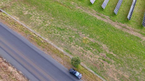 vehicle drives past solar panels along rural road in australia