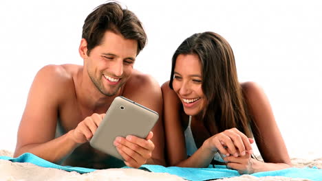 couple relaxing on the beach with a tablet