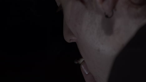 young man with cigarette smoking in a dark room