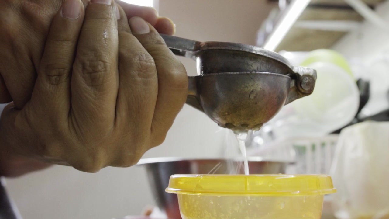 Mano exprimiendo limón para la preparación de albóndigas de pollo