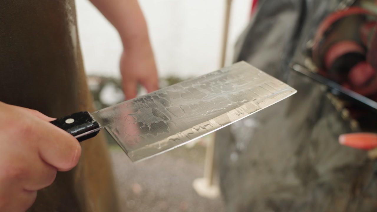 Close-up of hands inspecting a freshly cleaned Chinese cleaver knife in Malaysia, checking blade sharpness and surface quality after washing, highlighting precision and craftsmanship. UHD.