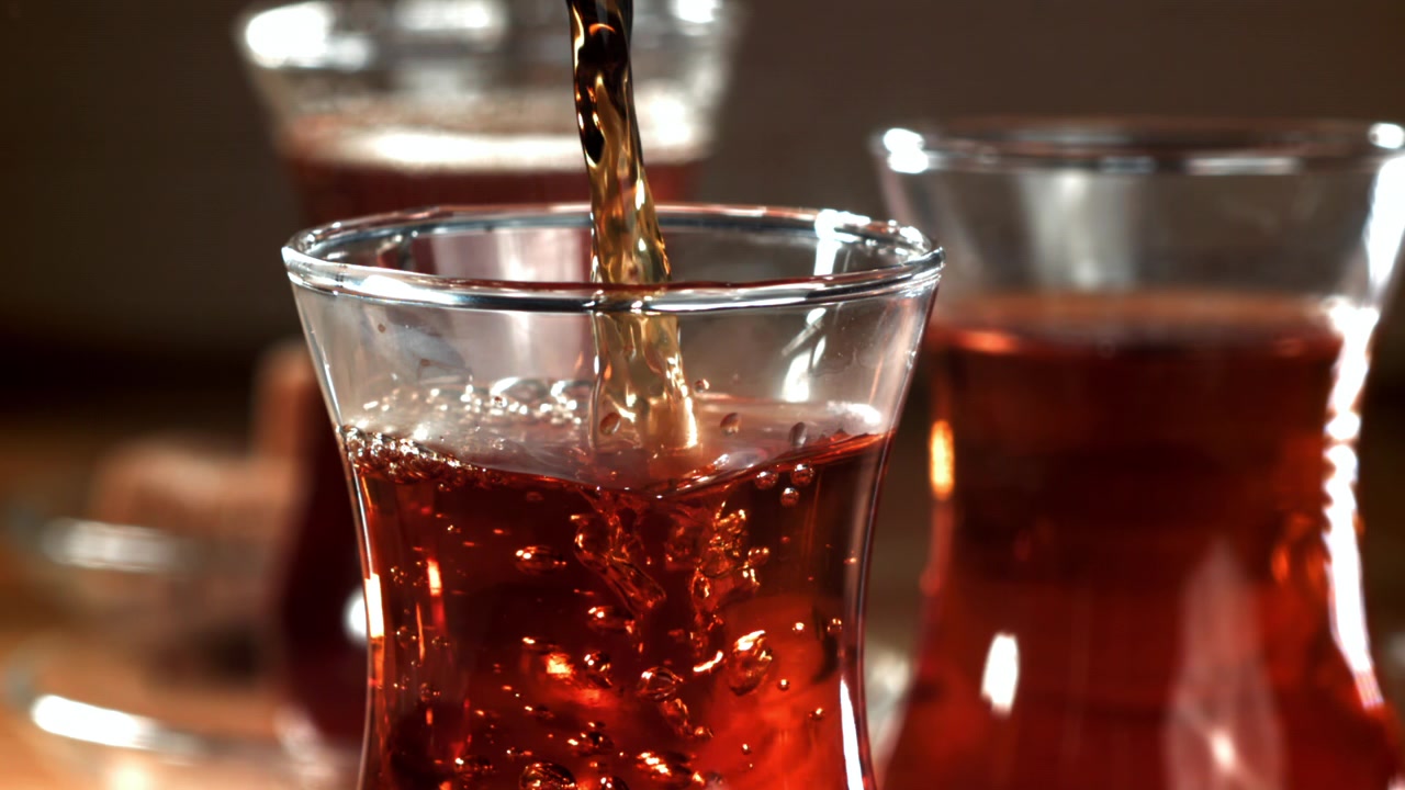 Bevanda rossa rinfrescante che riempie un bicchiere trasparente con bollicine