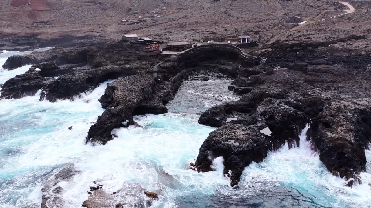 Raw power of sea collides, rugged stone formations near natural arch landmark