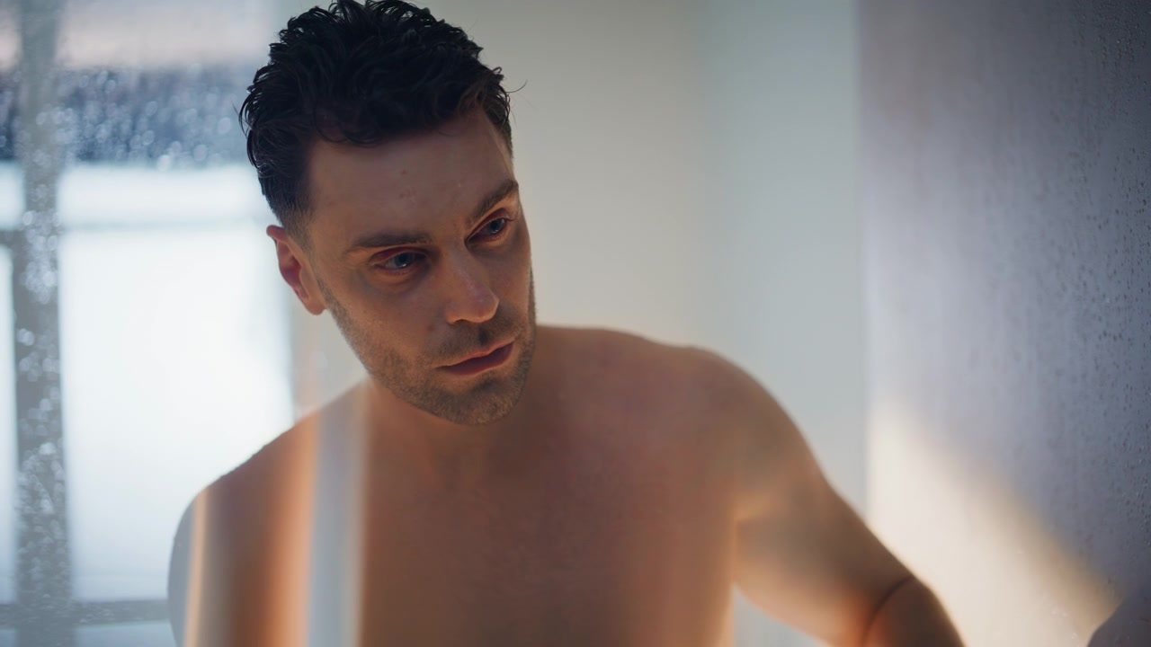 Ragazzo pensieroso a torso nudo che si passa le dita tra i capelli