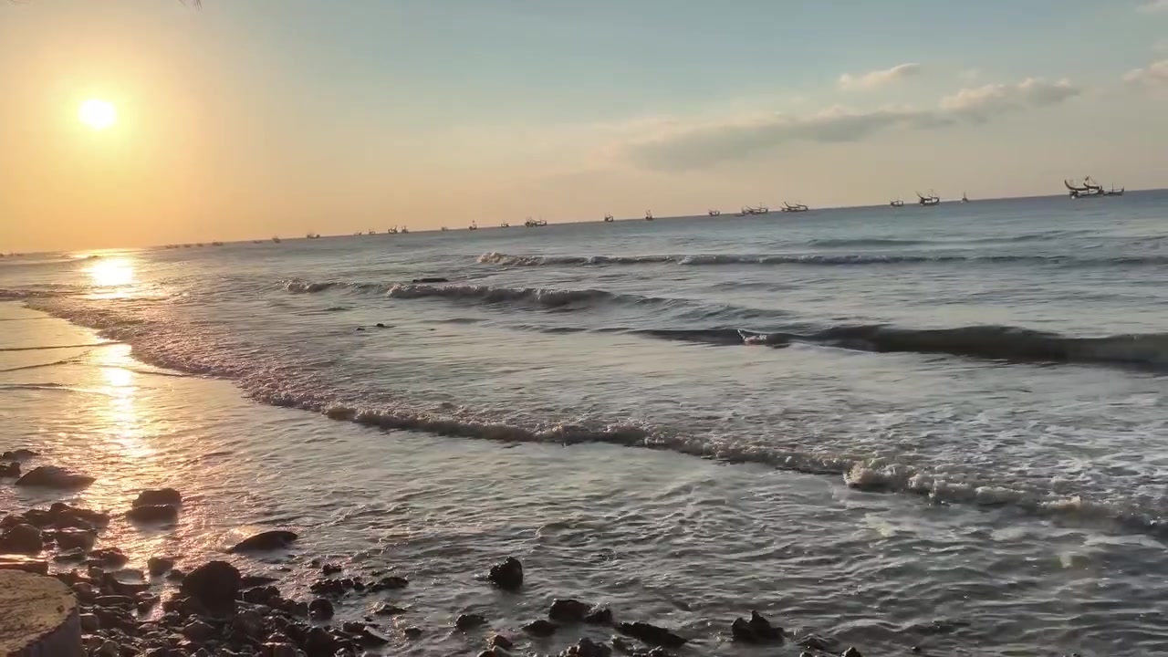 Onde oceaniche tranquille al tramonto con barche da pesca all'orizzonte