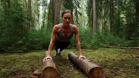 woman doing push-ups on logs in a forest