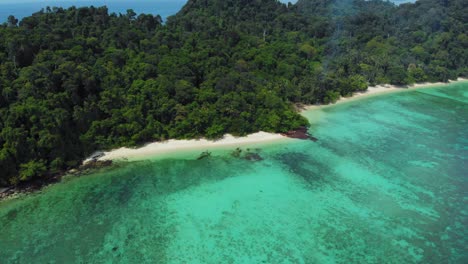 A-zoom-in-aerial-shot-of-a-stunning-tropical-island-and-its-white-sandy-beach