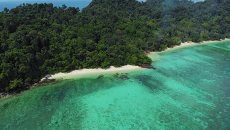 a zoom-in aerial shot of a stunning tropical island and its white sandy beach