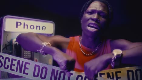 black rapper performing to camera behind caution tape at crime scene