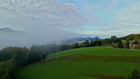 mist cloud above green hill with cottage in alpine countryside