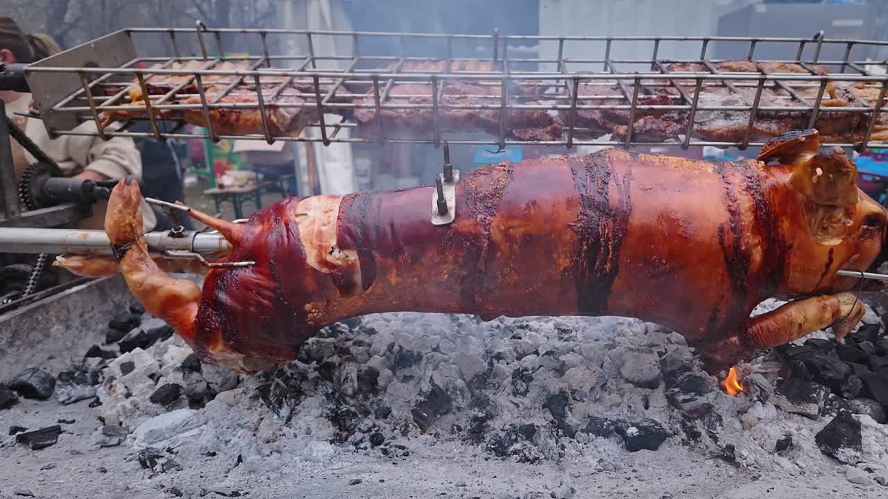 Pig on Spit and Pork meat Slow Roasting Over BBQ at food Festival SLIDE SHOT